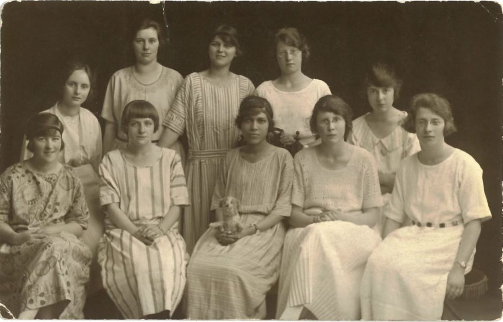 A black and white photo of ten young women in early 20th century summer dresses.