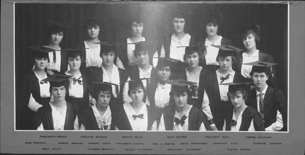 A black and white class photo of 19 female students in academic dress.